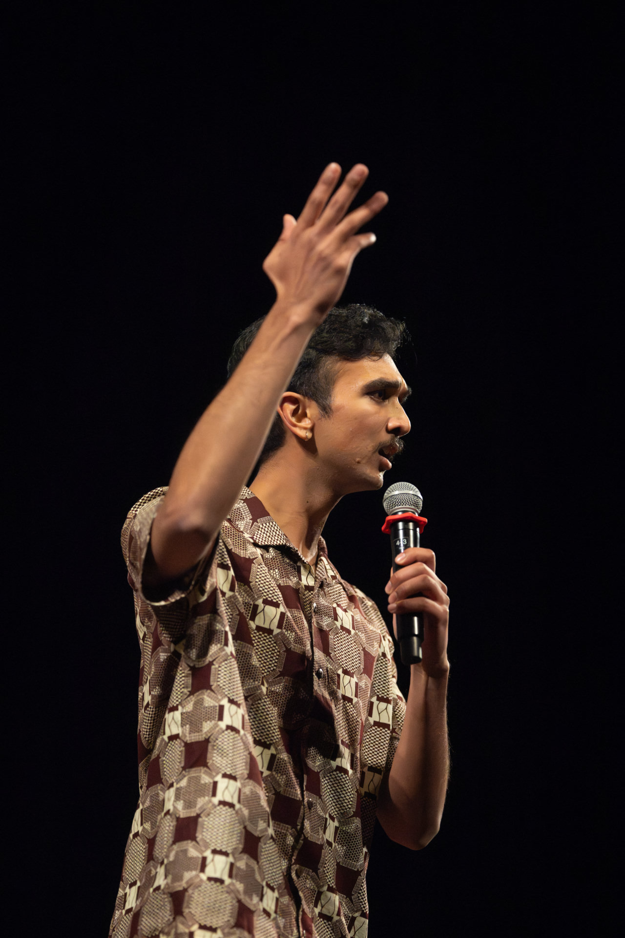 Atman speaking on stage with a microphone